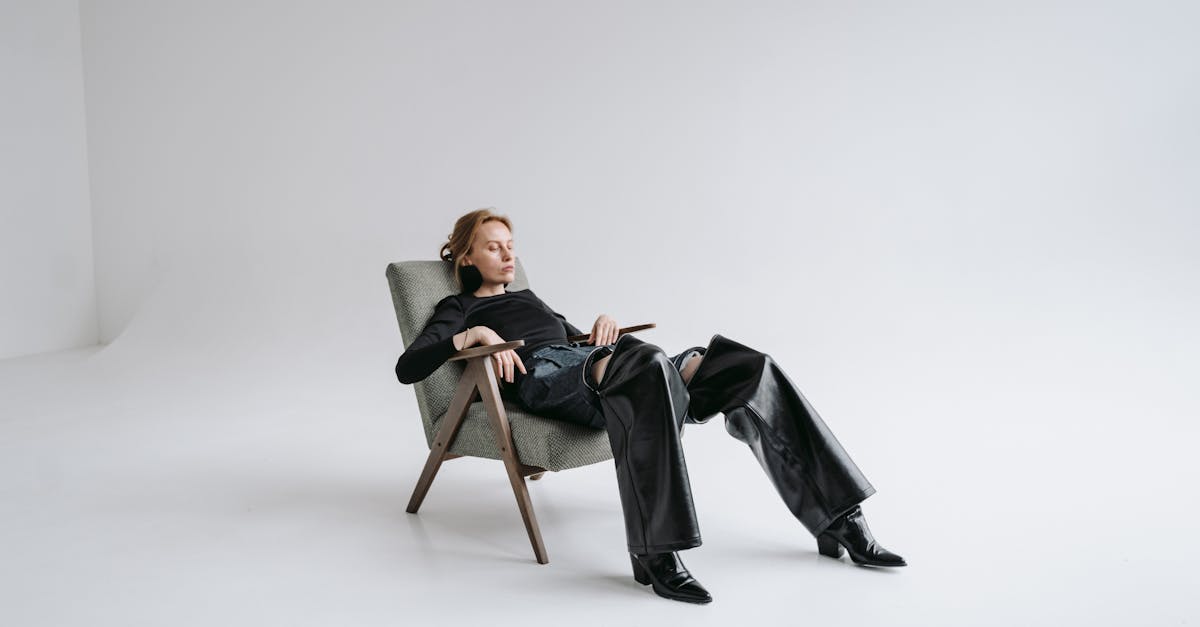 stylish woman in black leather outfit reclines in a minimalist studio with open space
