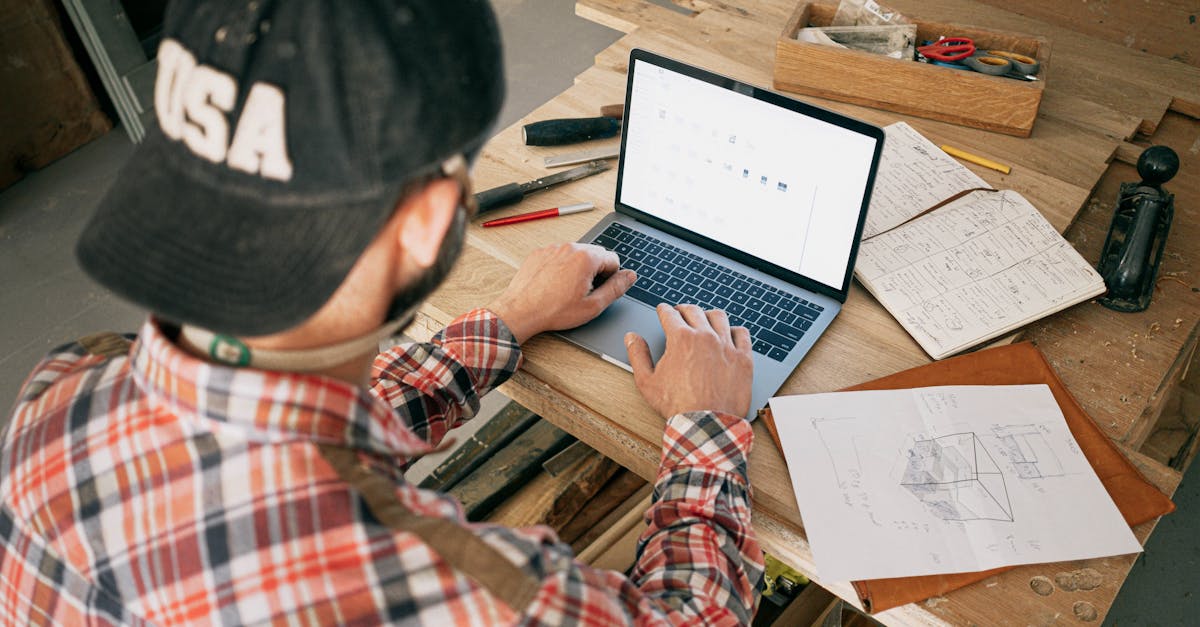 a woodworker in a workshop uses a laptop for furniture design planning and project management